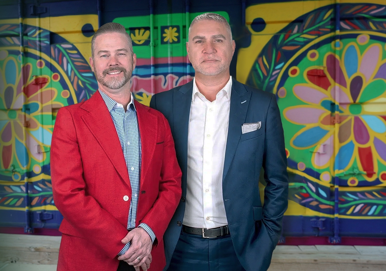 Dos abogados con los brazos cruzados frente a un mural colorido en un entorno urbano